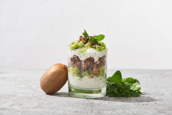fresh granola with kiwi and mint on concrete surface isolated on grey