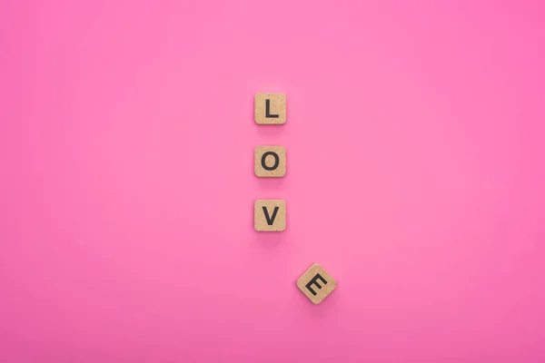ピンクの背景に隔離された木製の立方体に愛のレタリングのトップビュー — ストック写真