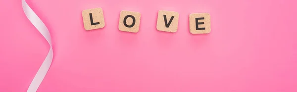 ピンクで隔絶された愛の文字が刻まれた曲線のリボンと木のブロックのトップビュー パノラマショット — ストック写真