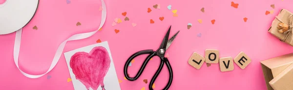 バレンタインコンフェッティ空コンパクトディスクはさみギフトボックスグリーティングカードピンクの背景に木製のキューブ上の愛のレタリングパノラマショット — ストック写真