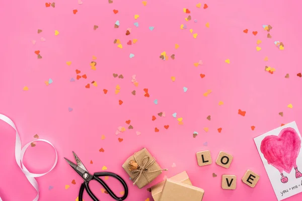 バレンタインコンフェッティ空コンパクトディスクはさみギフトボックスグリーティングカードピンクの背景に愛のレタリングとキューブ — ストック写真
