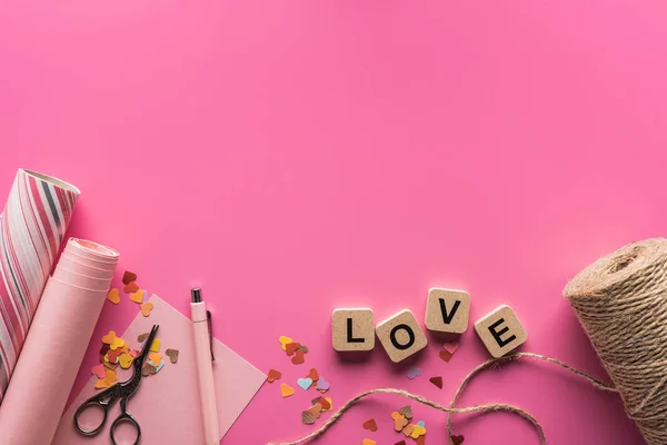 情人节装饰品 包装纸 细线的顶部视图 以及粉色背景的木制立方体上的情书 — 图库照片