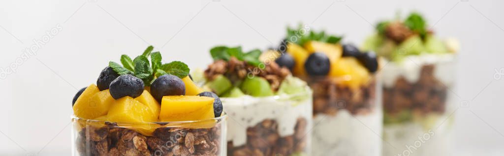 selective focus of fresh granola with kiwi and canned peach with blueberries isolated on white, panoramic shot