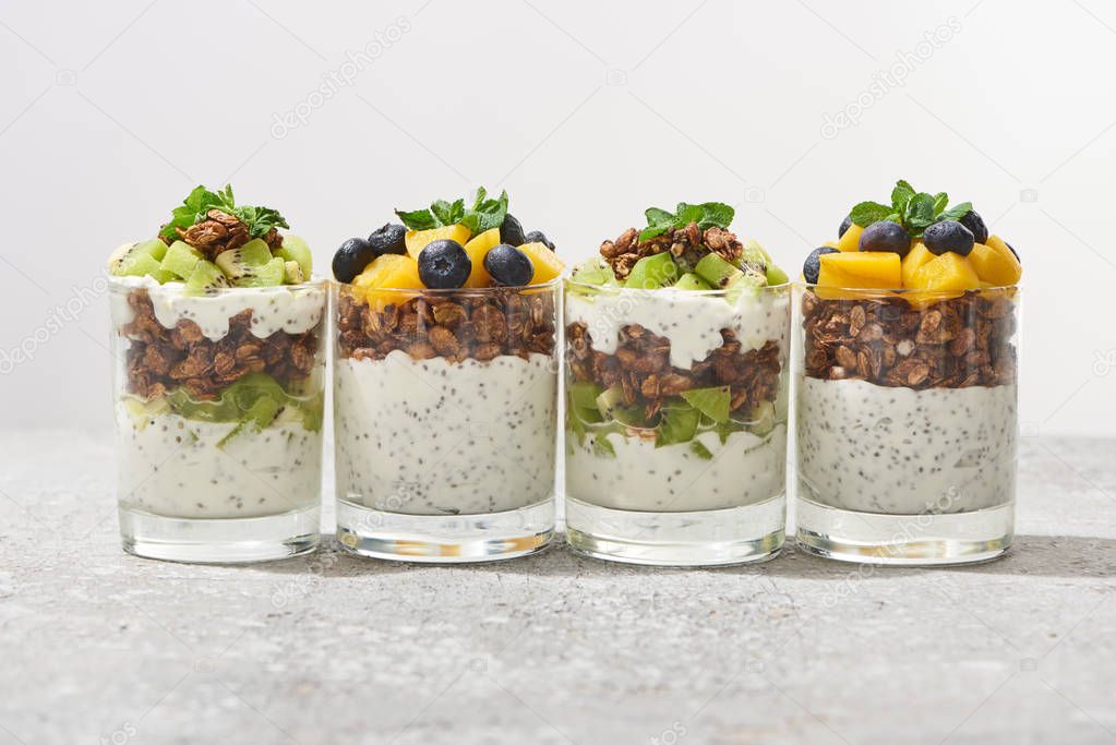 fresh granola with kiwi and canned peach with blueberries on grey concrete surface isolated on grey