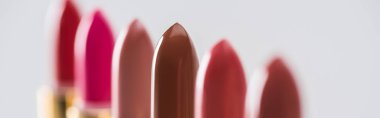 close up view of assorted lipsticks in luxury tubes in line on white background, panoramic shot clipart