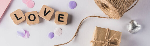 top view of valentines decoration, gift, twine and love lettering on cubes on white background, panoramic shot