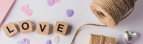 top view of valentines decoration, gift, twine and love lettering on cubes on white background, panoramic shot