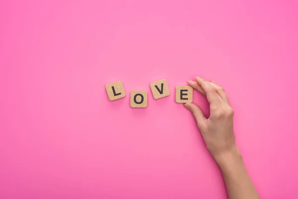 ピンクの背景に愛の文字でキューブを保持する女性の部分的なビュー — ストック写真