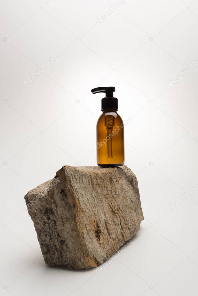 dispenser cosmetic bottle on stone on white background with back light