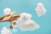dřevěná hračka letadlo létání mezi bílými nadýchané mraky z bavlněné vlny izolované na modré