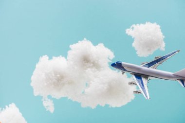 Beyaz pamuklu bulutların arasında uçan oyuncak uçak mavi üzerinde izole edilmiş pamuk yününden