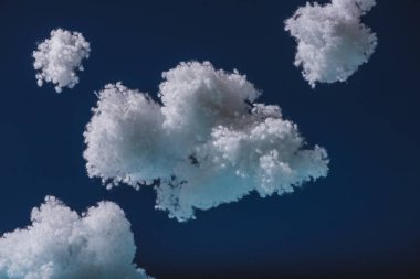 Koyu mavi üzerine izole edilmiş pamuklu beyaz bulutlar.