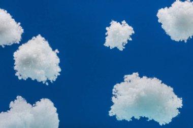 Beyaz tüylü bulutların arasında uçan ahşap oyuncak uçak mavi üzerinde yünlü pamuktan yapılmış.