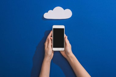 Mavi üzerine boş beyaz kağıt bulutun yanında akıllı telefon tutan bir kadın görüntüsü.