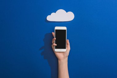Mavi üzerine boş beyaz kağıt bulutun yanında akıllı telefon tutan bir kadın görüntüsü.