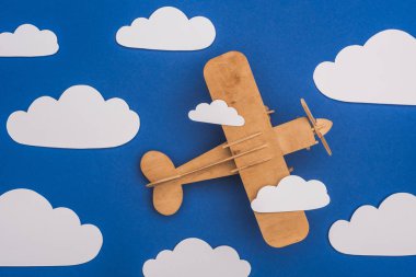 top view of wooden plane in blue sky with paper cut white clouds clipart