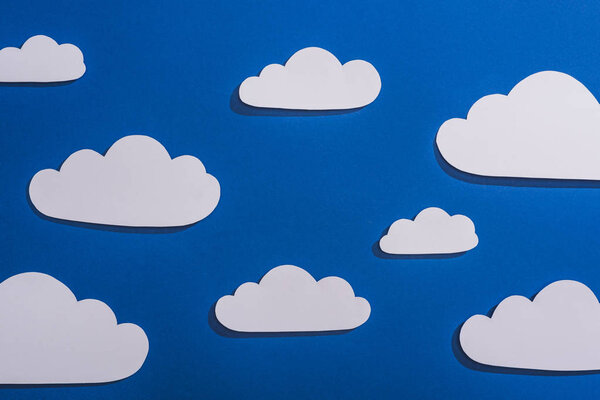 top view of white paper cut clouds on blue background