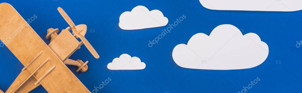 top view of wooden plane in blue sky with paper cut white clouds, panoramic shot