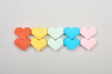 Gri arkaplanda renkli kağıt kalplerin üst görünümü