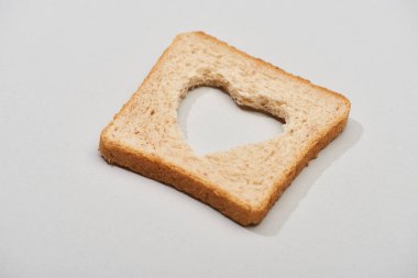 Gri arka planda oyulmuş kalp şeklinde ekmek dilimi