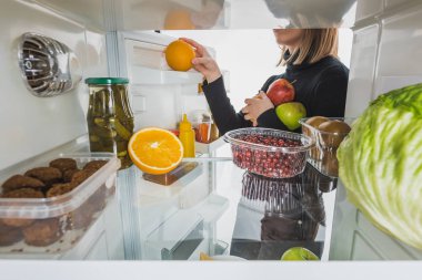 Cropped view of woman taking ripe fruits from refrigerator with food isolated on white clipart