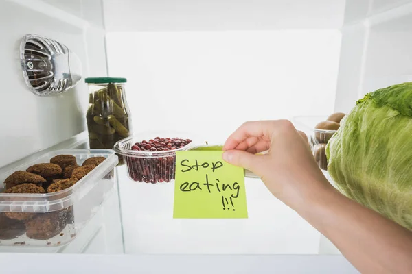 Cropped view of woman holding card with stop eating lettering with food in fridge at background, isolated on white — Stock Image Cropped View Woman Holding Card Stop Eating Lettering Food Fridge Stock Photo