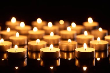 selective focus of burning candles glowing in darkness clipart