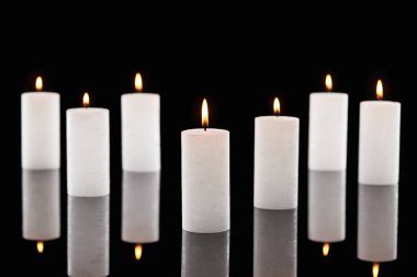 selective focus of burning white candles glowing isolated on black clipart