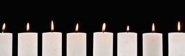 burning white candles glowing in line isolated on black, panoramic shot clipart