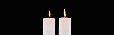two burning white candles glowing isolated on black, panoramic shot clipart