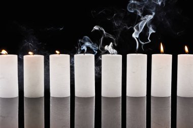 Siyah arkaplanda dumanı olan sönmüş beyaz mumlar yakıyor.