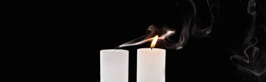 burning and extinct white candles with smoke on black background, panoramic shot clipart