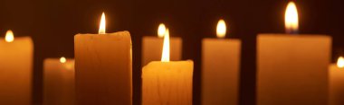 selective focus of burning candles glowing in dark, panoramic shot clipart