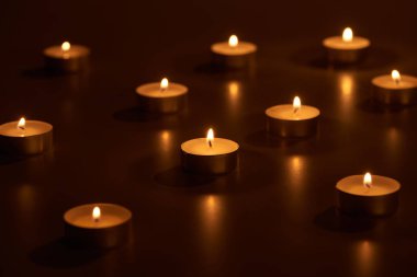 selective focus of burning white candles glowing in dark clipart