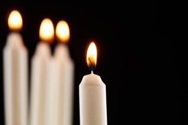 selective focus of burning white candle glowing isolated on black clipart