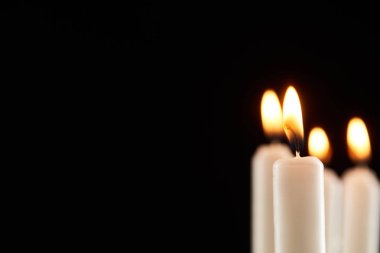 selective focus of burning white candle glowing isolated on black clipart