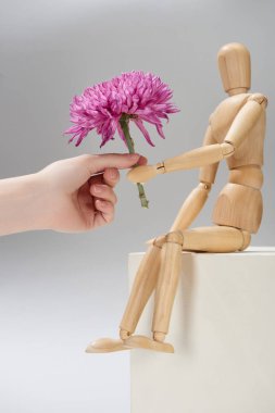 Kırpılmış kadın manzarası ve gri arka planda paskalya kuşu tutan tahta bebek.