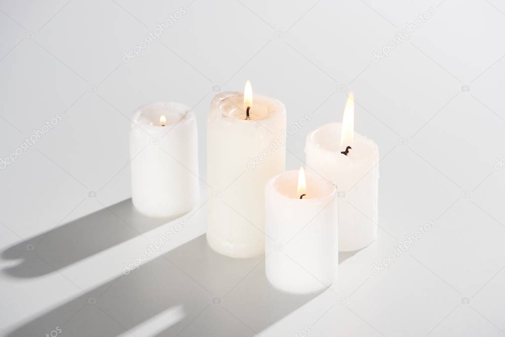 burning candles glowing on white background with shadow