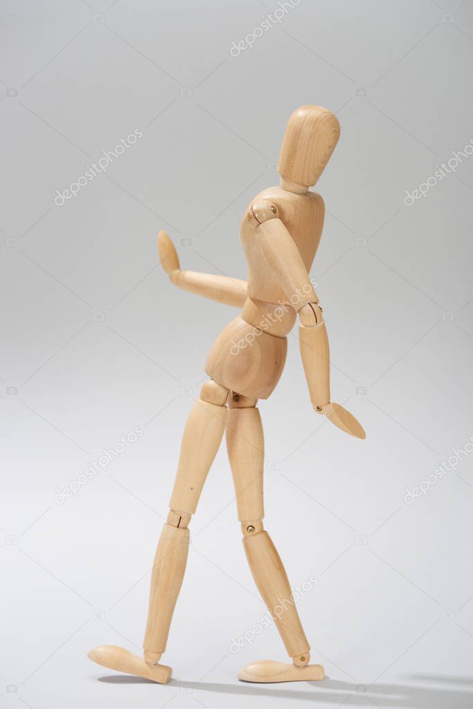 Wooden doll with hinges on grey background