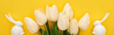 top view of tulips and white Easter bunnies on colorful yellow background, panoramic shot clipart