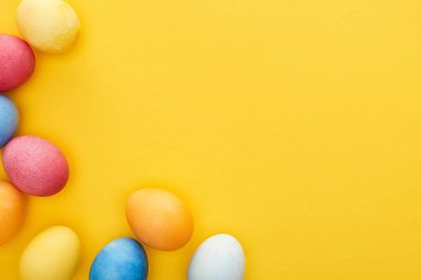 Sarı zemin üzerinde boyanmış Paskalya yumurtalarının fotokopi alanı ile üst görünümü