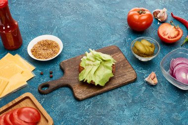 Mavi desenli yüzeyde taze hamburger malzemeleri var.