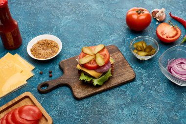 Mavi desenli yüzeyde taze hamburger malzemeleri var.