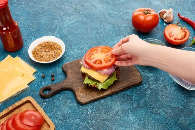 Mavi desenli yüzeyde enfes taze hamburger pişiren kadın manzarası.