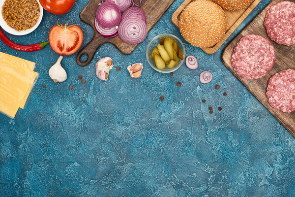 вид сверху на свежие ингредиенты бургера на голубой текстурированной поверхности
