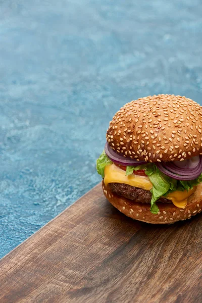 Delicious Cheeseburger Wooden Board Blue Textured Surface — Stock Photo, Image