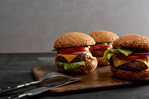 Pyszne Świeże Cheeseburgery Mięsne Drewnianej Desce Pobliżu Sztućców — Zdjęcie stockowe