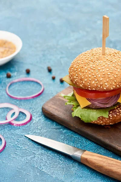 Selective Focus Knife Delicious Cheeseburger Wooden Board Blue Textured Surface — Stock Photo, Image