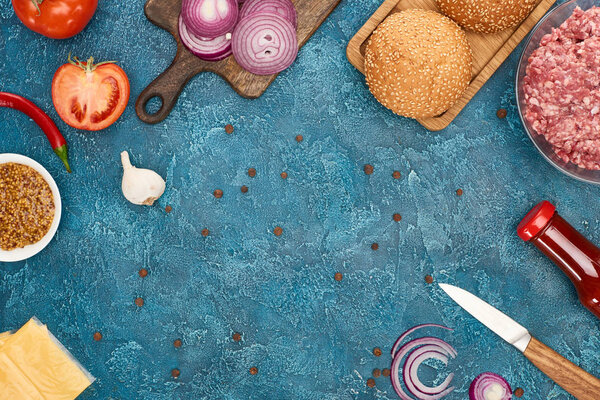 вид сверху на свежие ингредиенты бургера на голубой текстурированной поверхности
