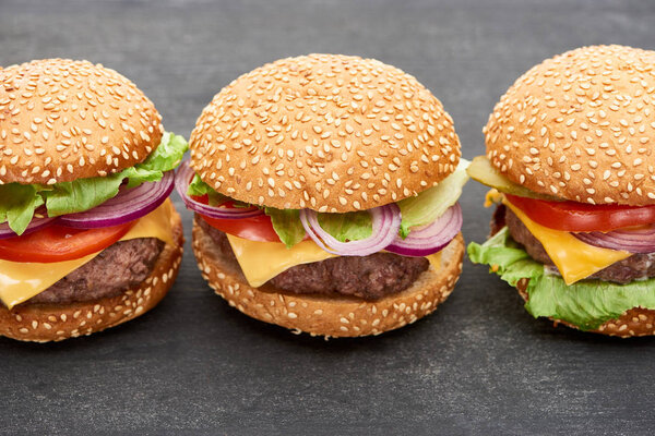 close up view of delicious fresh cheeseburgers on black table
